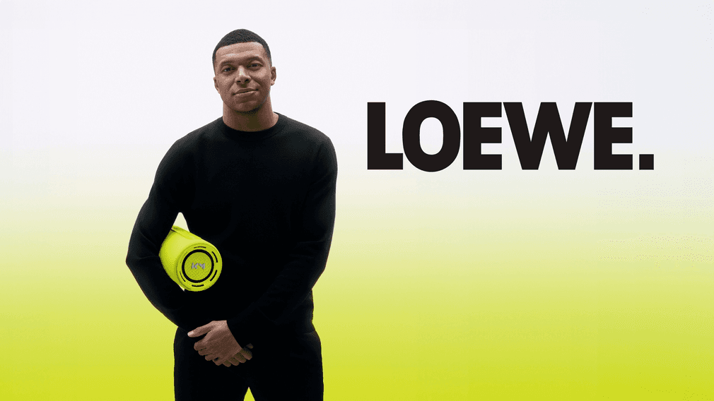 Kylian Mbappé holding the Loewe We.HEAR Pro speaker beside the LOEWE wordmark